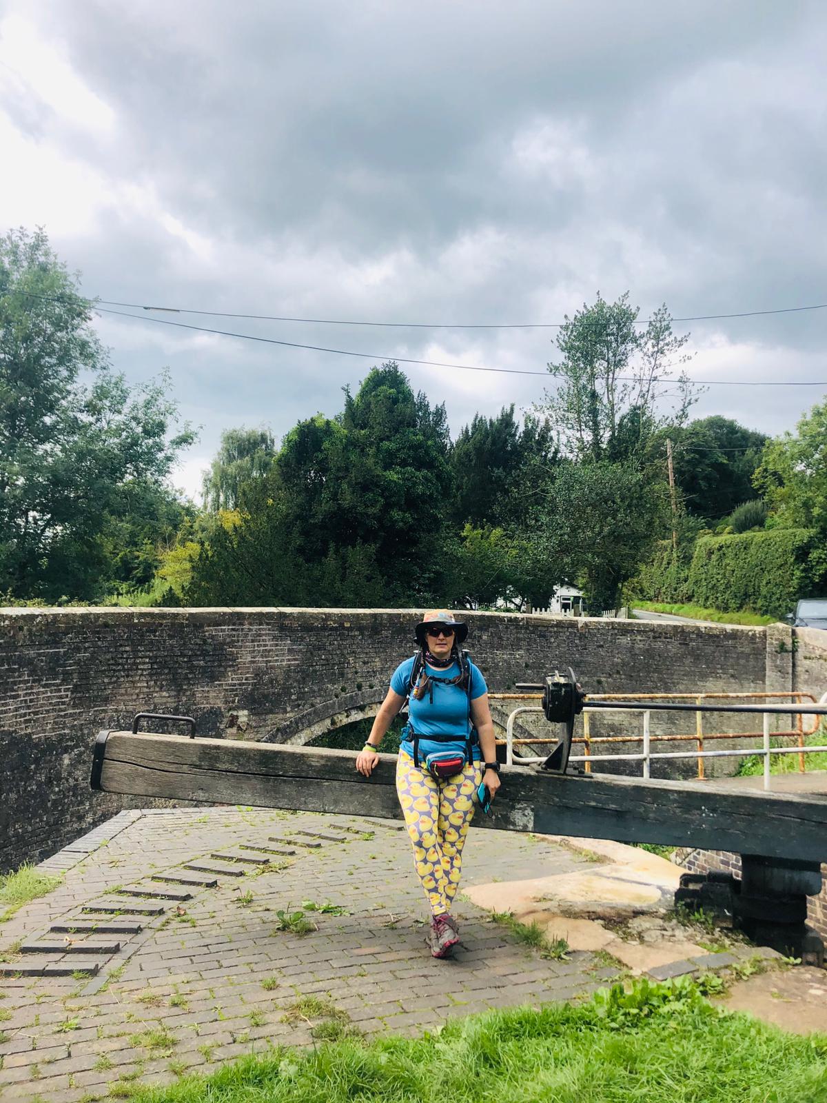 A woman in walking kit sitting on a canal lock gate