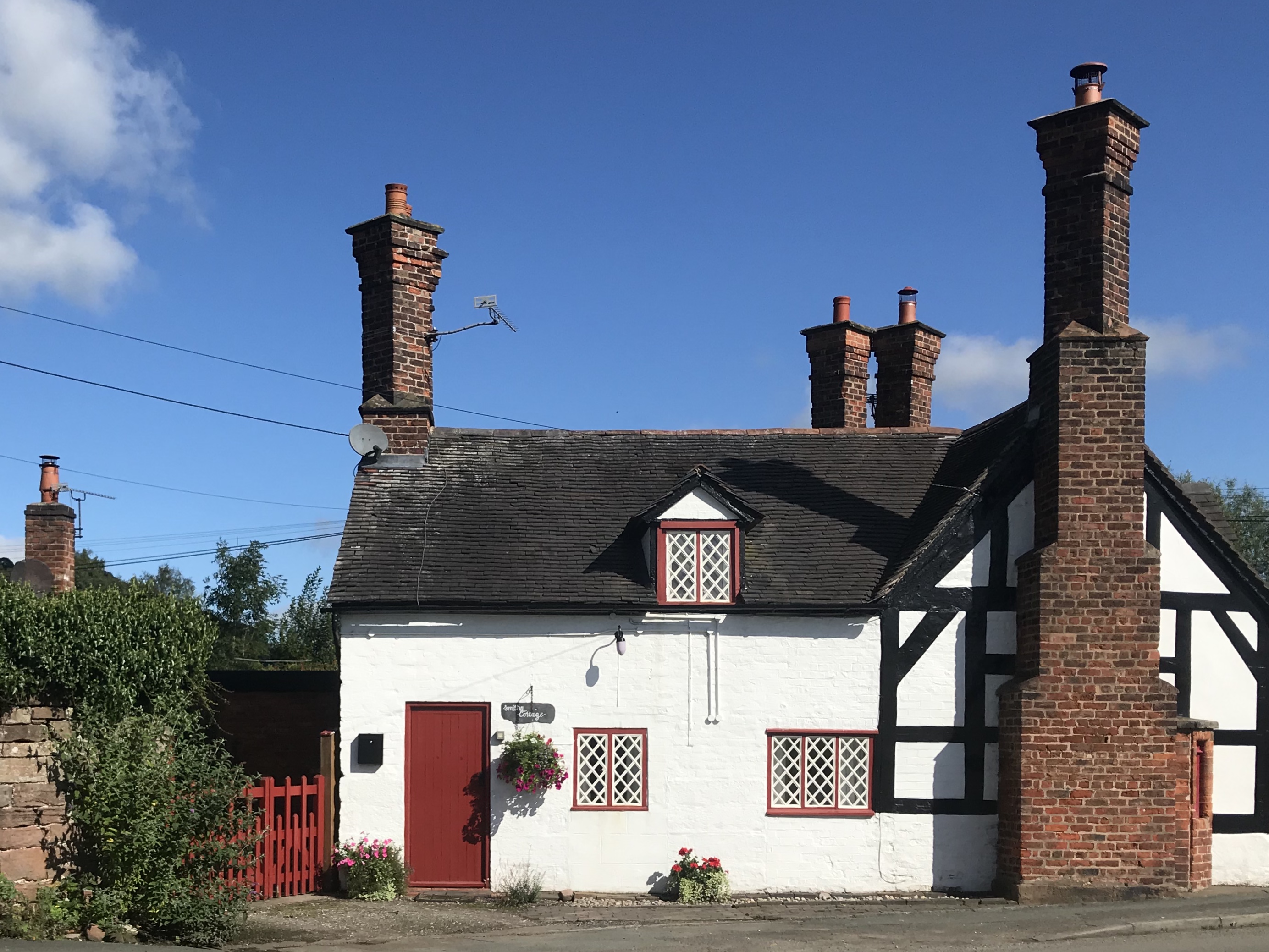 A small black and white cottage with large red brick chimneys