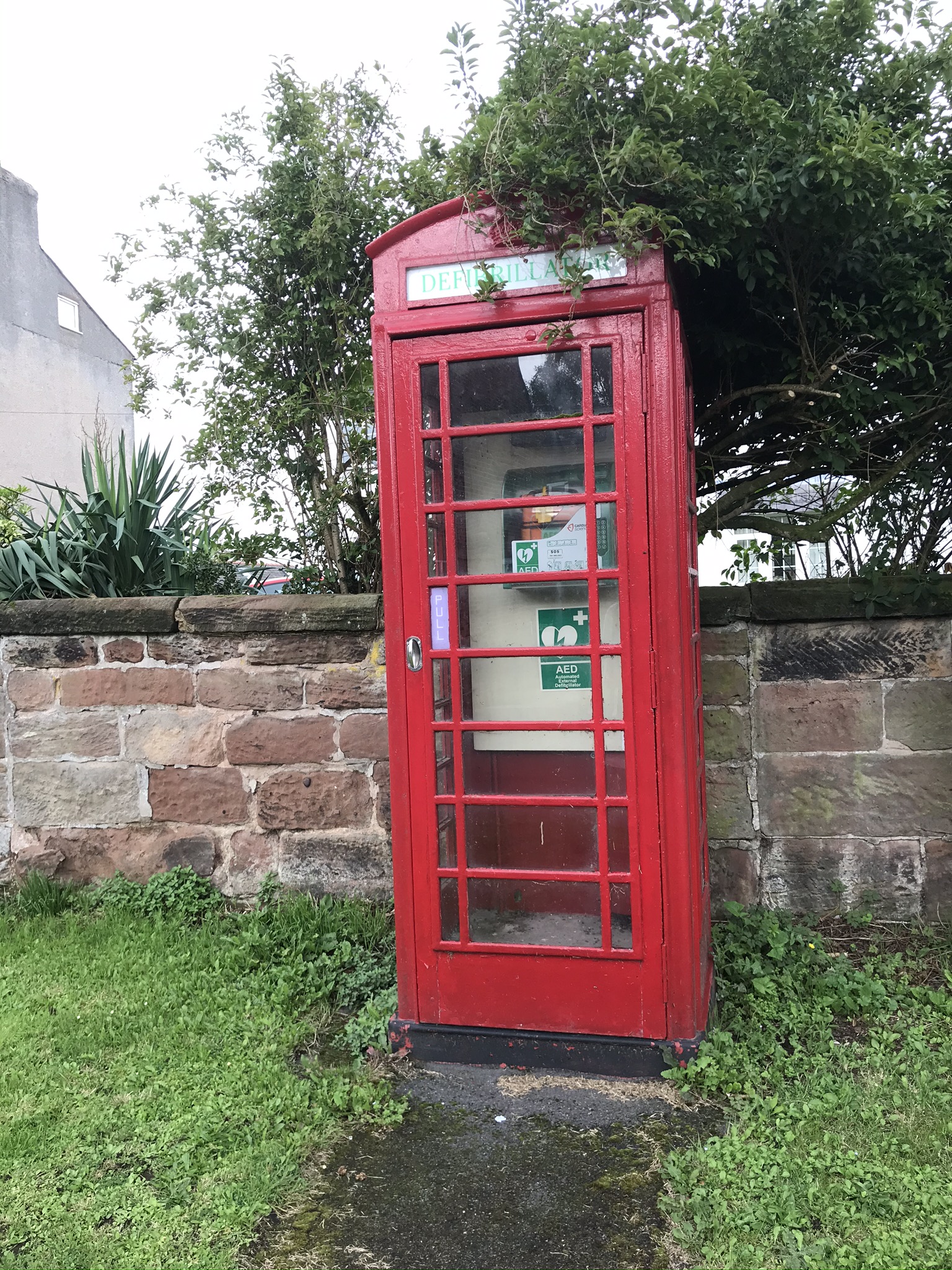 An old red telephone box containing an automated external defibrilator