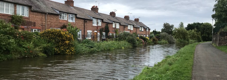 A row of brick cottages backing onto the canal with a two path on the opposite bank