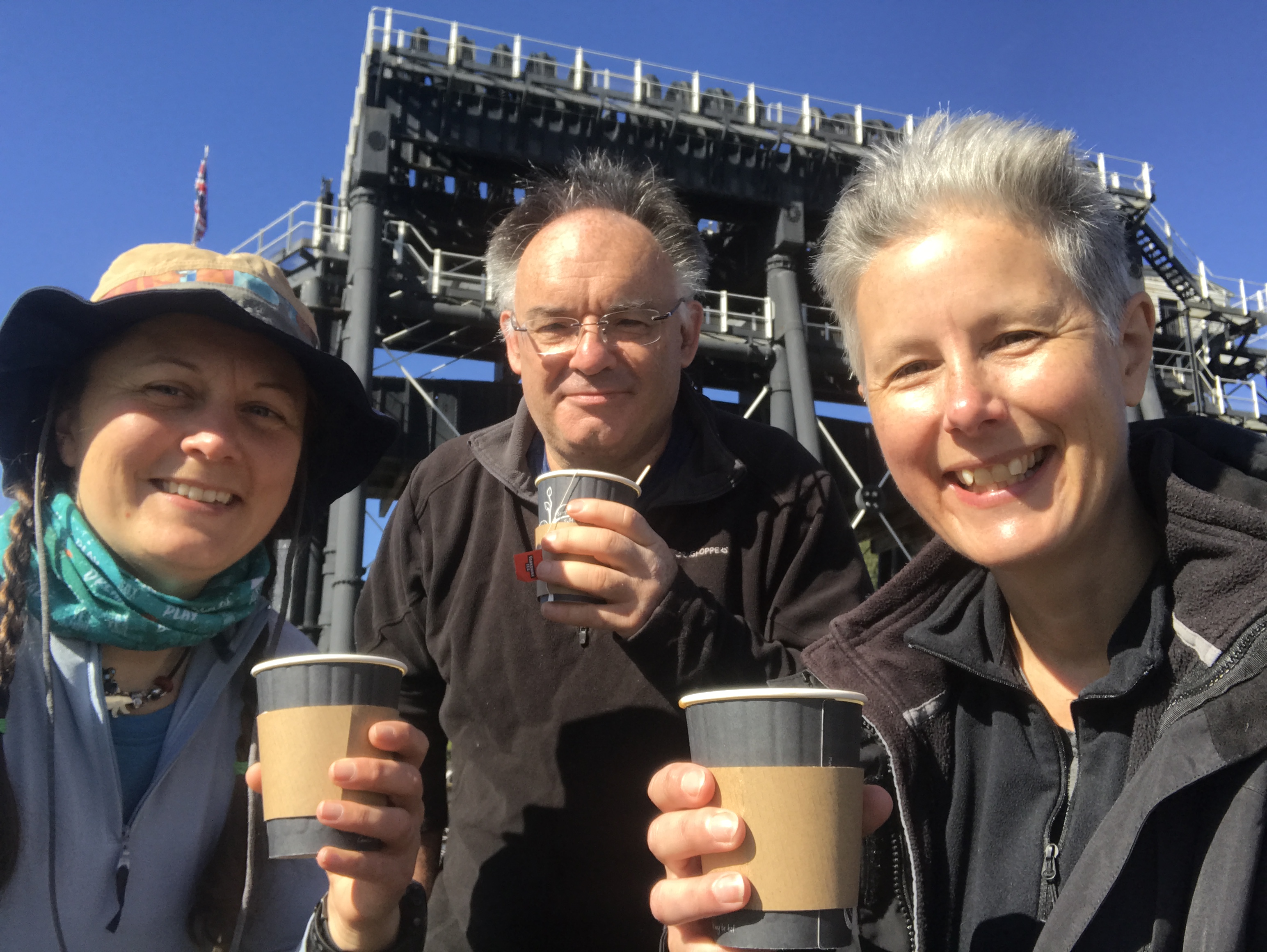 a selfie of three people with paper cups of tea in front of the Anderton boat lift.