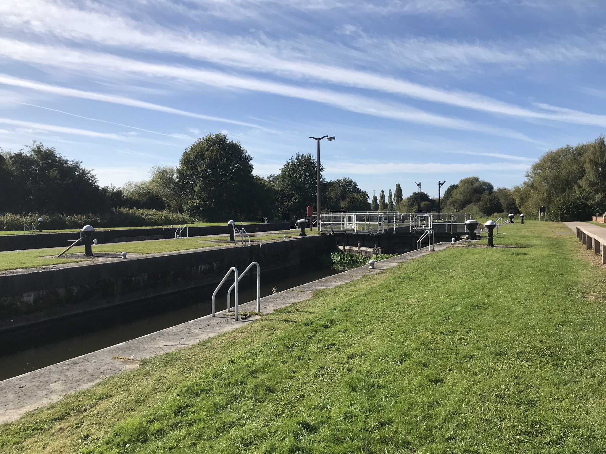 A lock gate with blue skies and mown grass banks