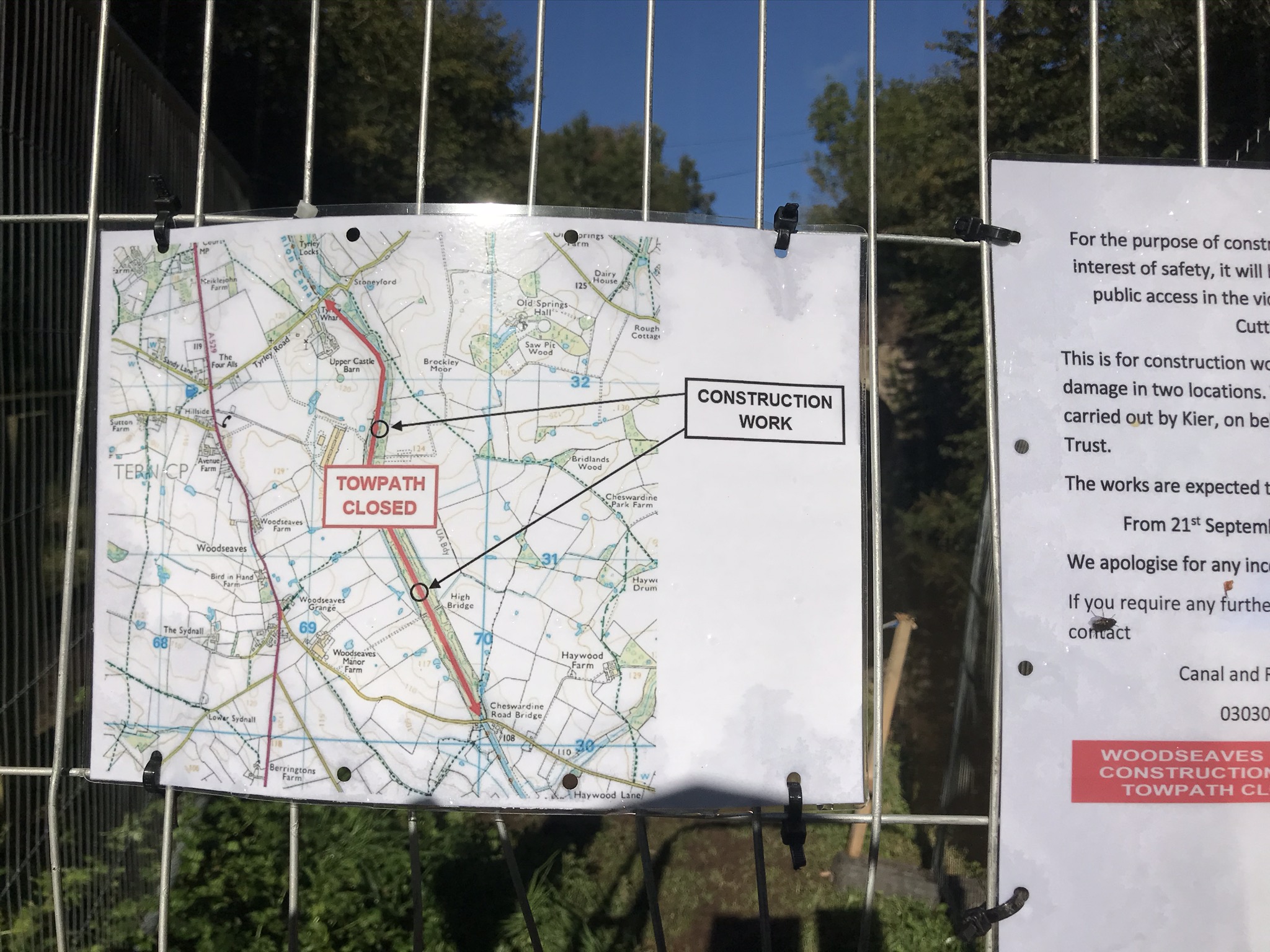 A construction work sign tied to a wire fence. The sign is a map showing a section of the footpath is closed with two areas of construction.