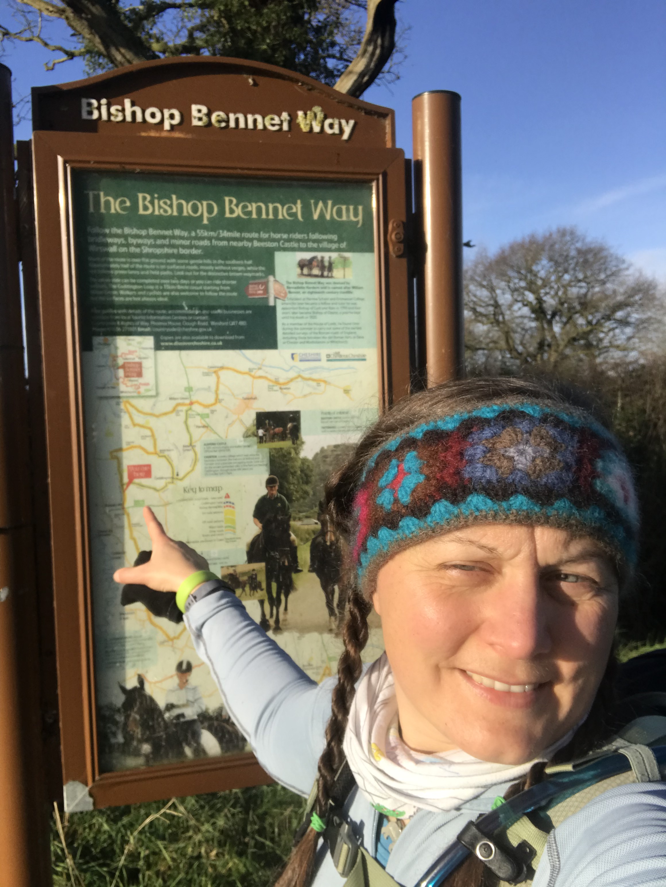 a woman wearing a knitted headbad pointing at a location on a large information board map