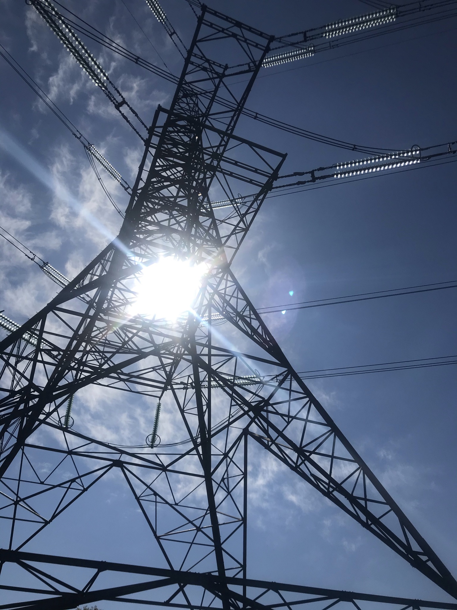 Sun behind a metal electricity pylon