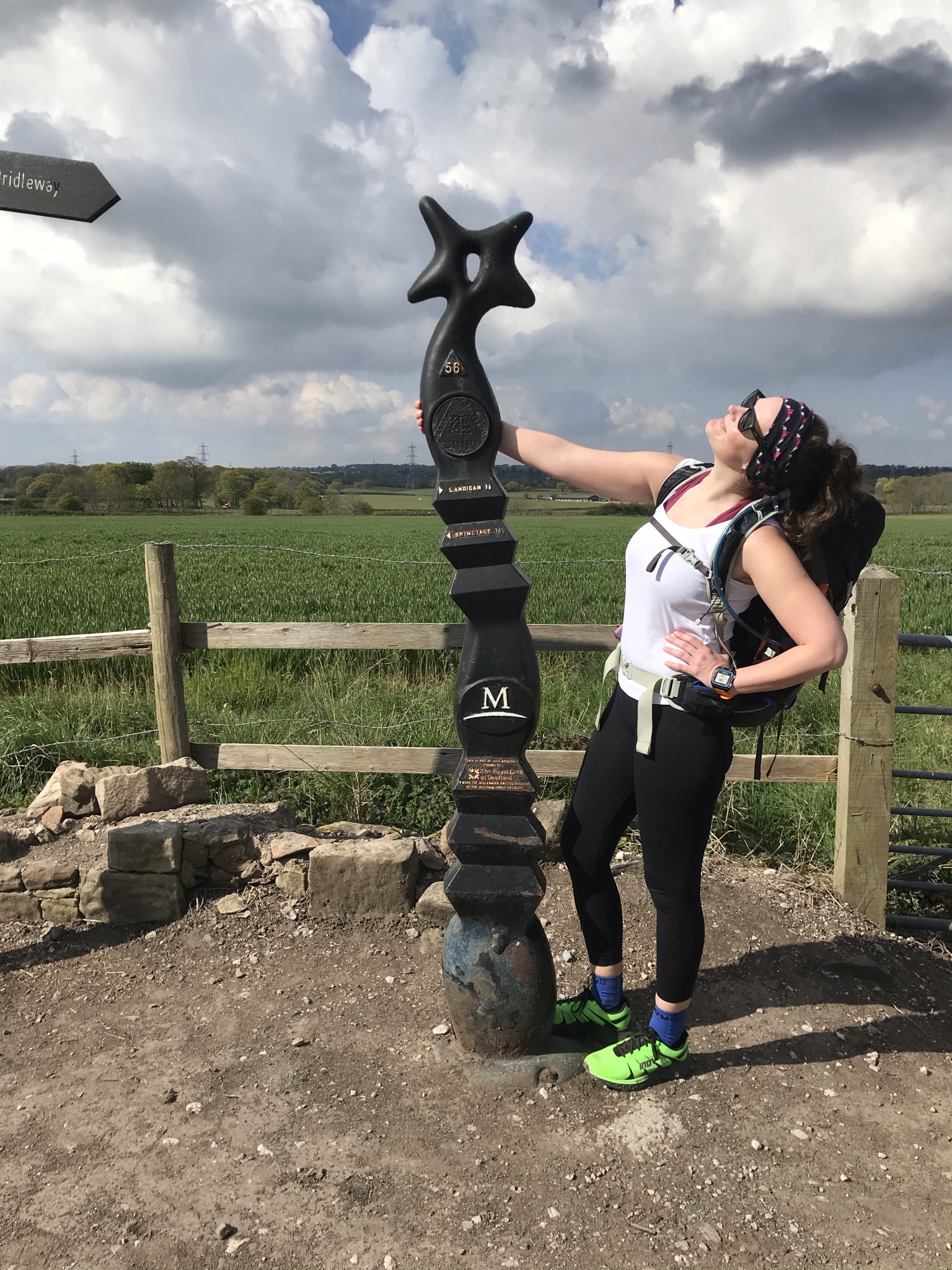 Sarah poses looking at cloudy but sunny sky by a Millennium Cycle trails post.e