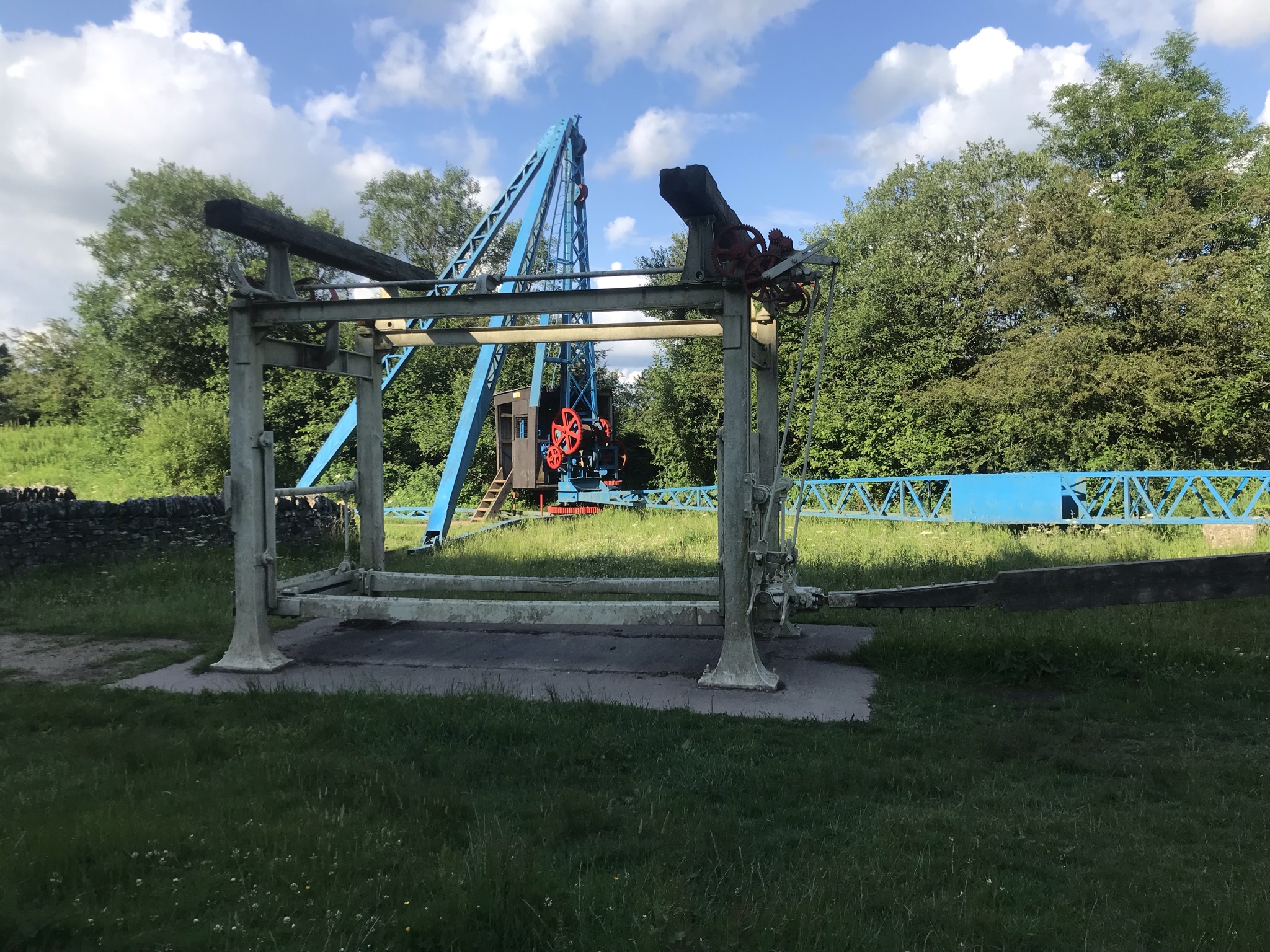 Old machinery brightly painted in front of trees