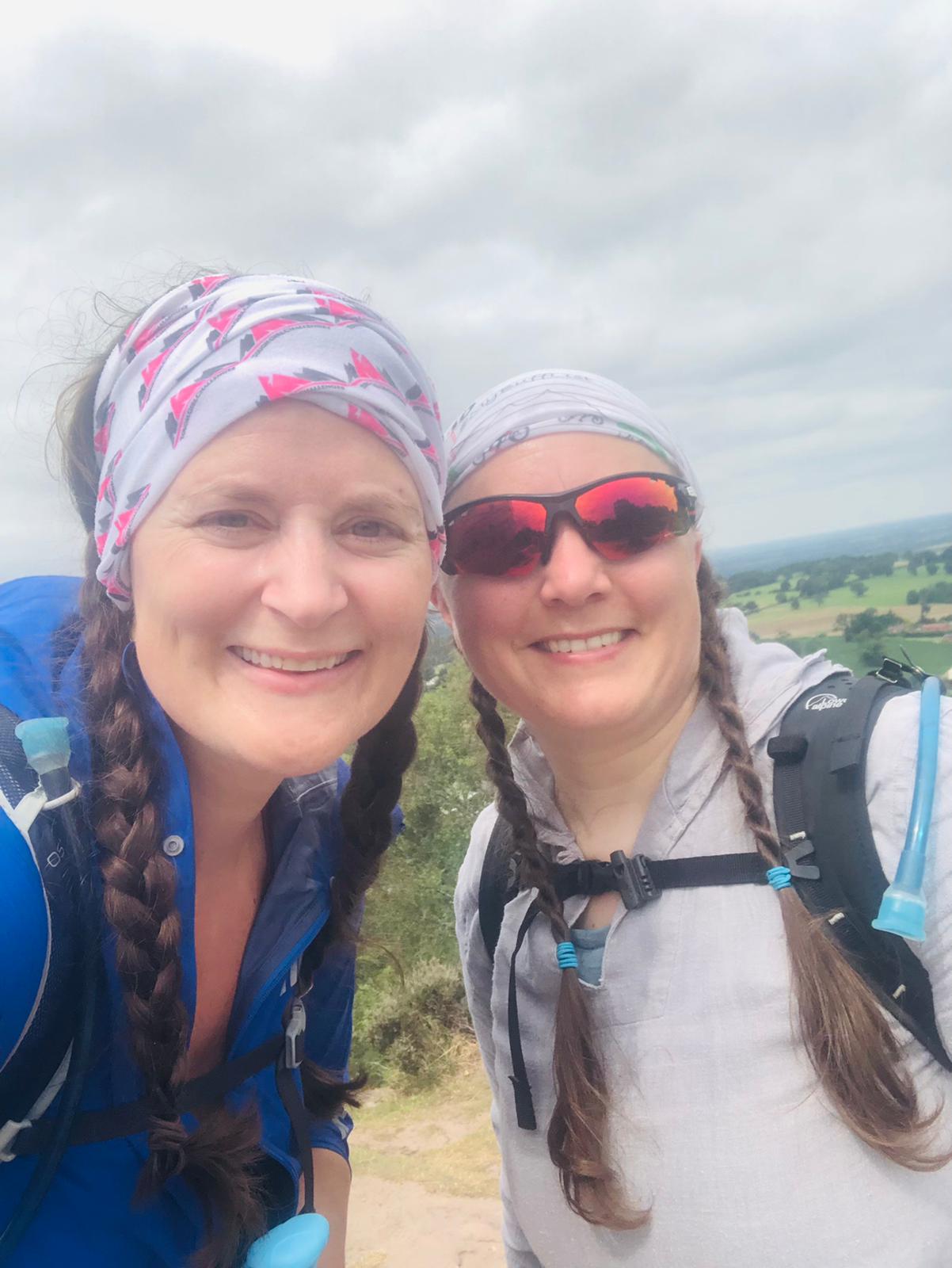 Sarah and Ellen smile at the camera on top of a hill