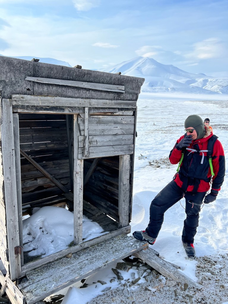Out guide stood next to a standing but battered wooden shed. You can just see the holes for the toilet at the back!