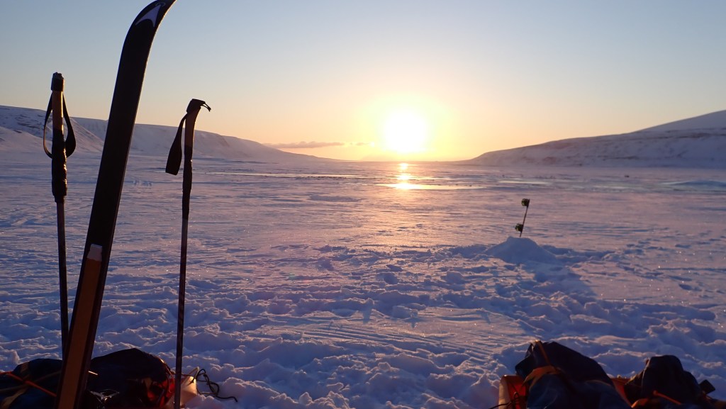 A very low sun making the snowy valley pink