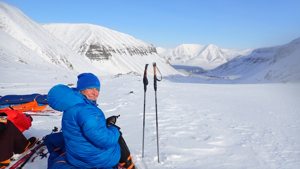 My tent buddy in a bright blue down jacket with a view down the glacier to the town